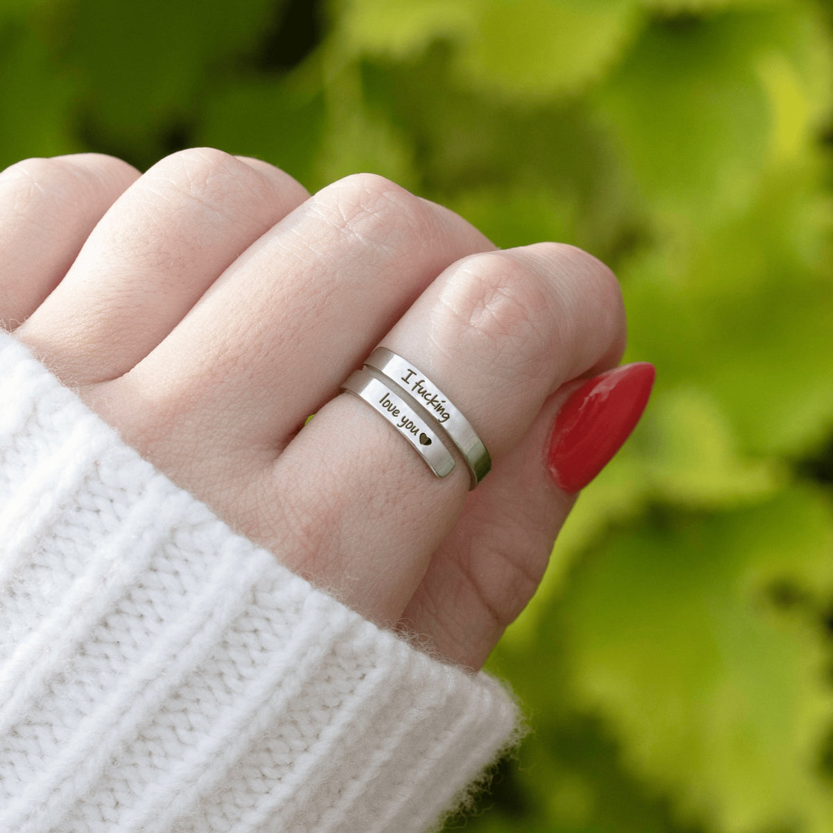 Stainless steel wrap ring engraved 'I fucking love you' worn on a finger